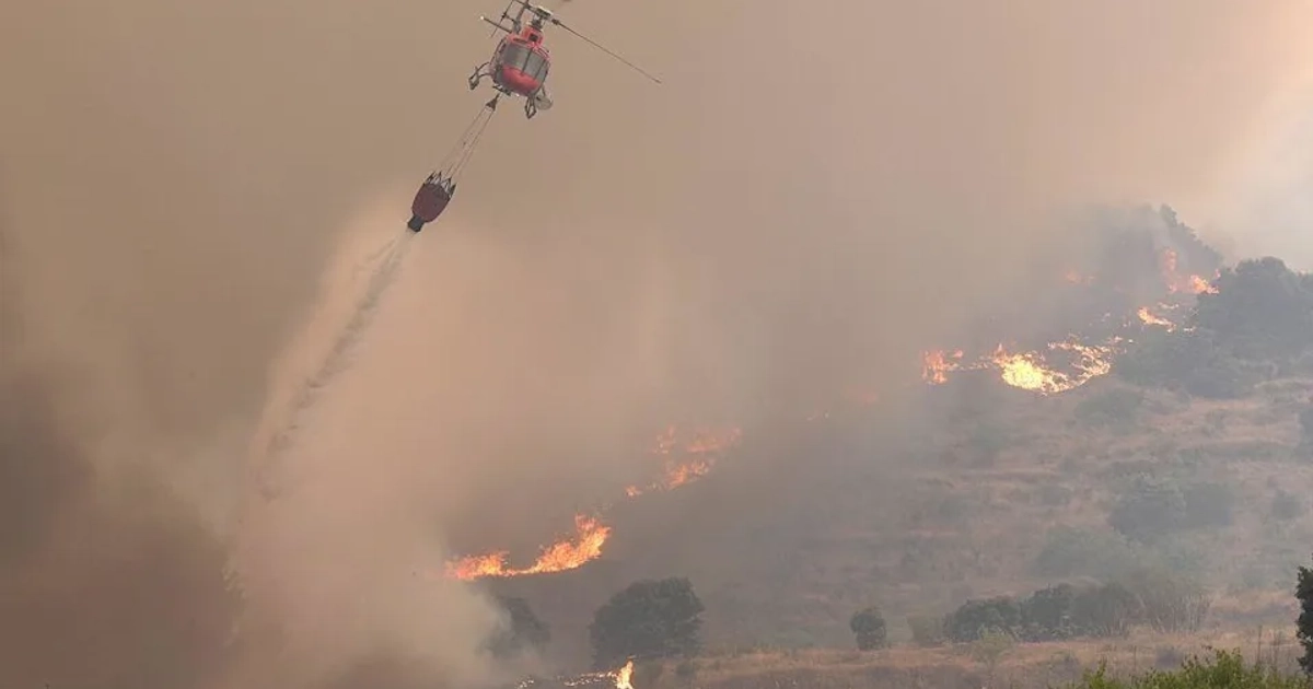 Un helicóptero de bomberos arroja agua sobre un incendio forestal en la zona de Cebreros, cerca de Ávila. [AFP via Getty Images]