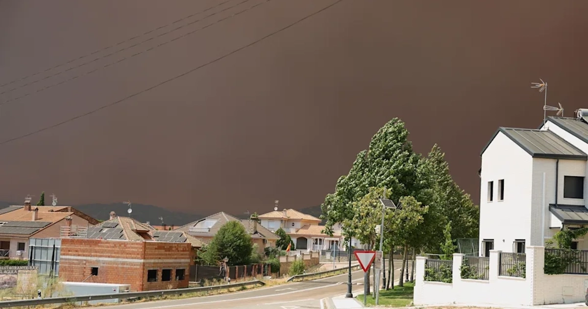 El humo de un incendio forestal oscurece el cielo sobre las viviendas de Quijorna, en la provincia de Madrid. [EPA]