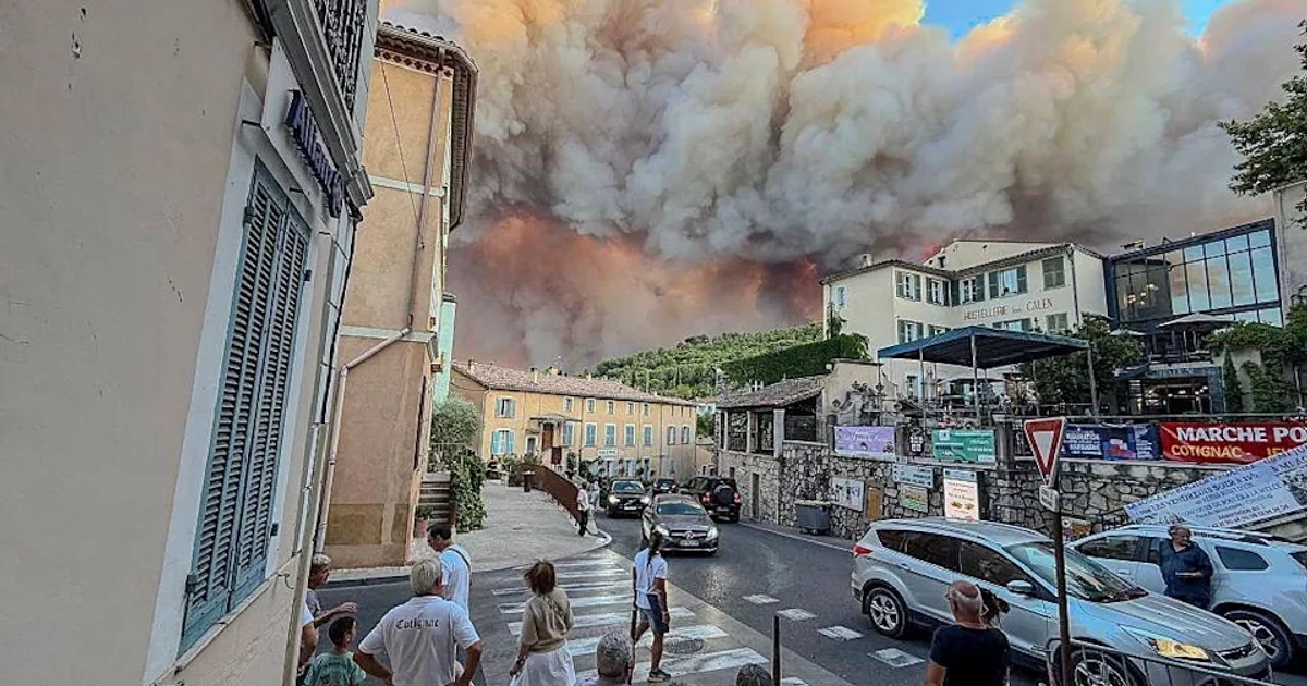 Varios transeúntes observan el humo y las llamas de un incendio forestal en Cotignac, Francia. [Getty Images]