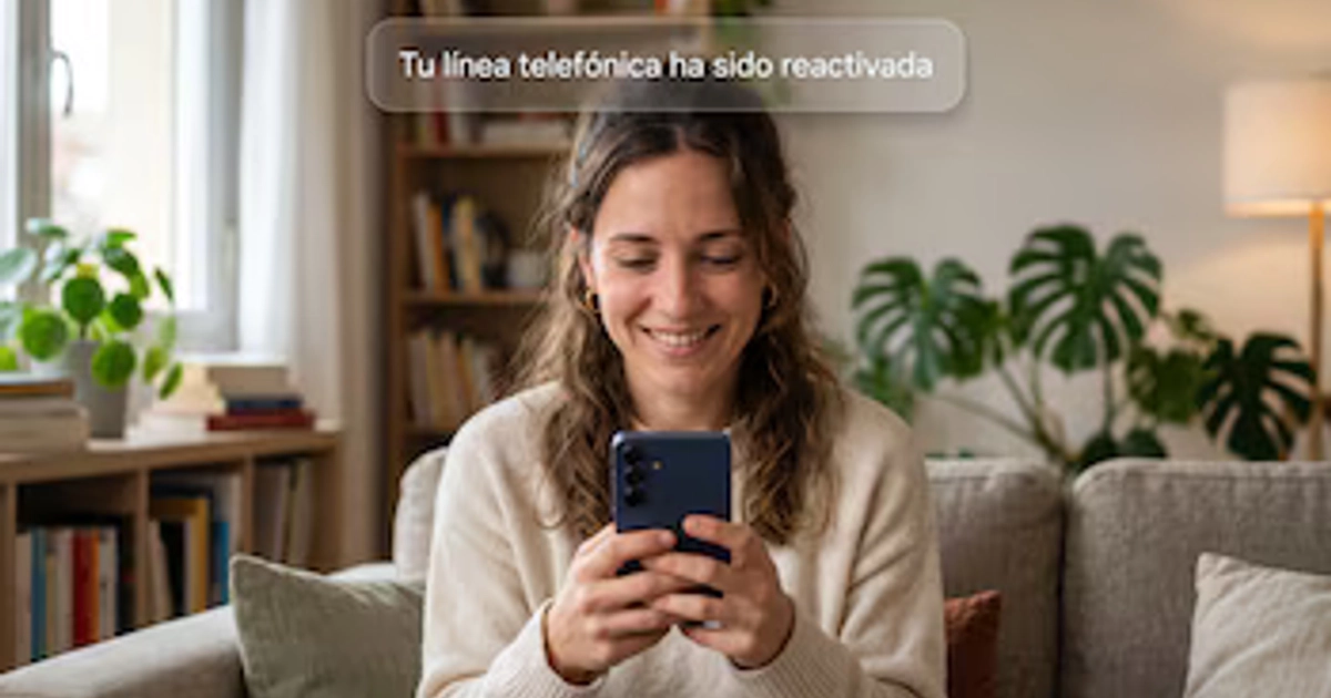 Mujer con jersey beige sonríe mientras mira su teléfono móvil azul. Sobre la imagen, un mensaje dice: “Tu línea telefónica ha sido reactivada”