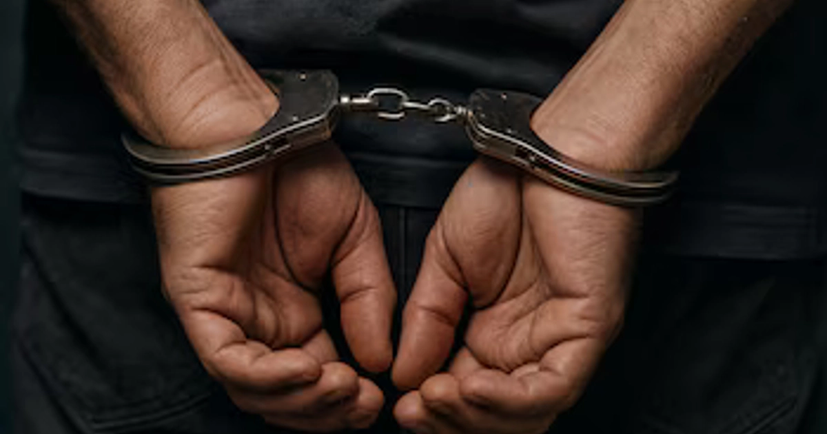 Las manos de un hombre están sujetas a la espalda con esposas metálicas de seguridad.