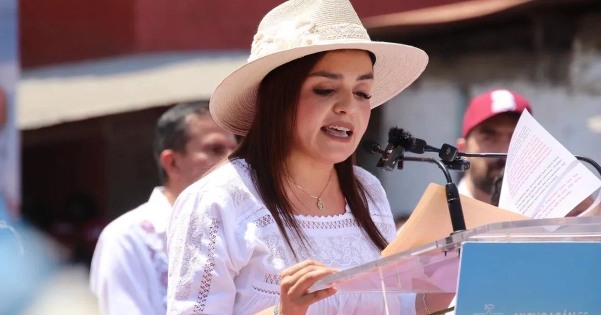 Grecia Quiroz se dirige al público desde un podio, solicitando a Claudia Sheinbaum atender las demandas ciudadanas ante la violencia en Uruapan. (@GreciaMich2027)