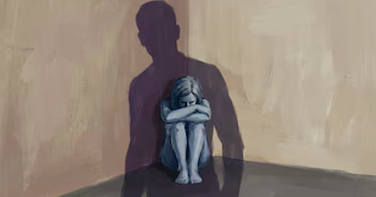 Una mujer sentada en un rincón con la cabeza apoyada en sus brazos ilustra el impacto emocional del abuso interpersonal frente a la silueta de un hombre. (Imagen Ilustrativa Infobae)