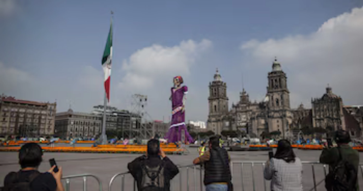 Varias personas fotografían la Catrina monumental de 32 metros instalada en el Zócalo de la Ciudad de México antes de la apertura oficial de la ofrenda. (ANDREA MURCIA /CUARTOSCURO.COM)