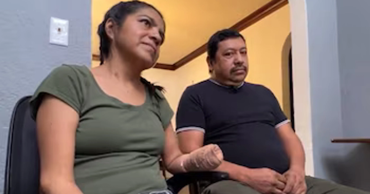 Una mujer con camiseta verde y la mano vendada está sentada al lado de un hombre con camiseta negra