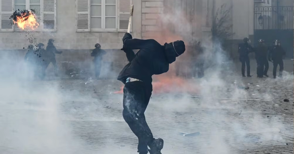 Un manifestante lanza material incendiario durante una manifestación para protestar contra el