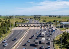 Una autopista de varios carriles con automóviles y camiones que se aproximan a una estación de peaje en una zona rural