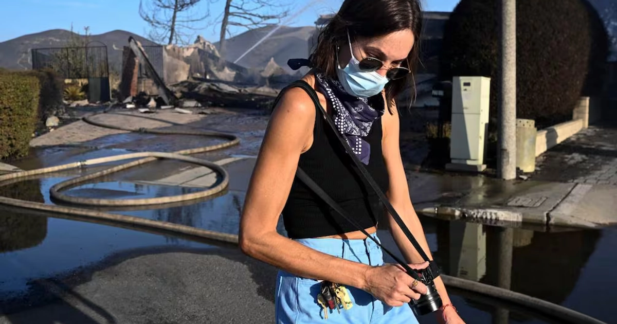 La residente Ashley Jennett camina frente a una vivienda que se incendió durante el incendio Norte este viernes 16 de octubre de 2026, en San Juan Capistrano, California. Foto: AP/Denis Poroy